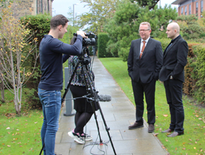 Photo of two academics being interviewed in front of a video camera